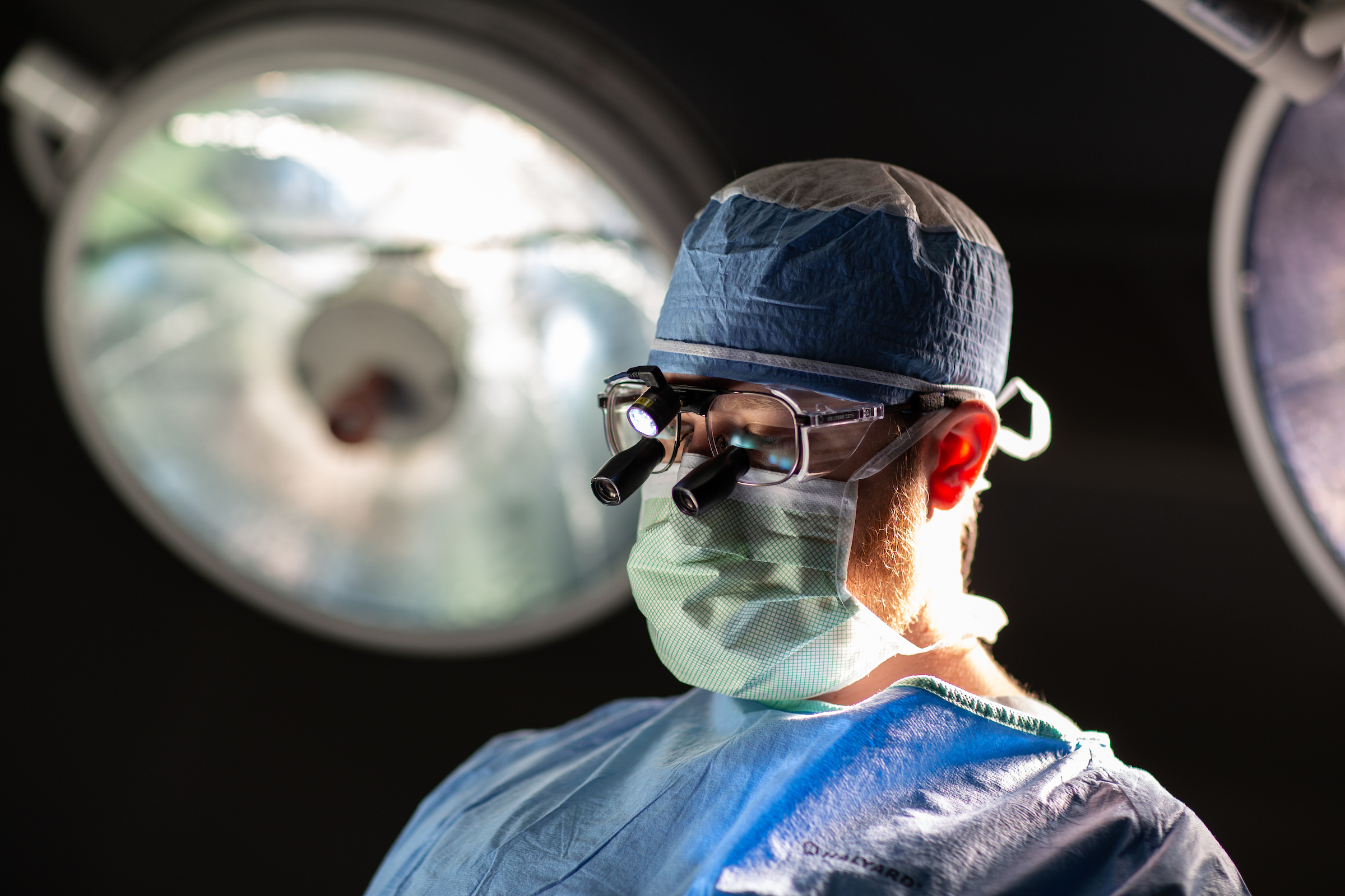 A UF Health Pediatric Neurosurgeon wears a mask, glasses, and cap as he performs a surgery.