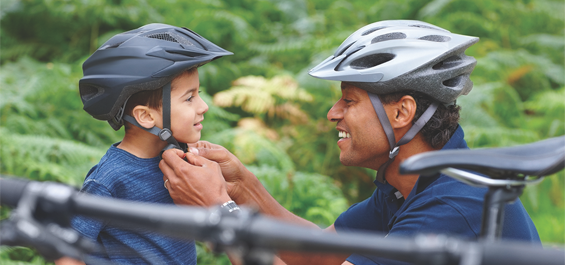 Man helps boy put on bicycle helmet