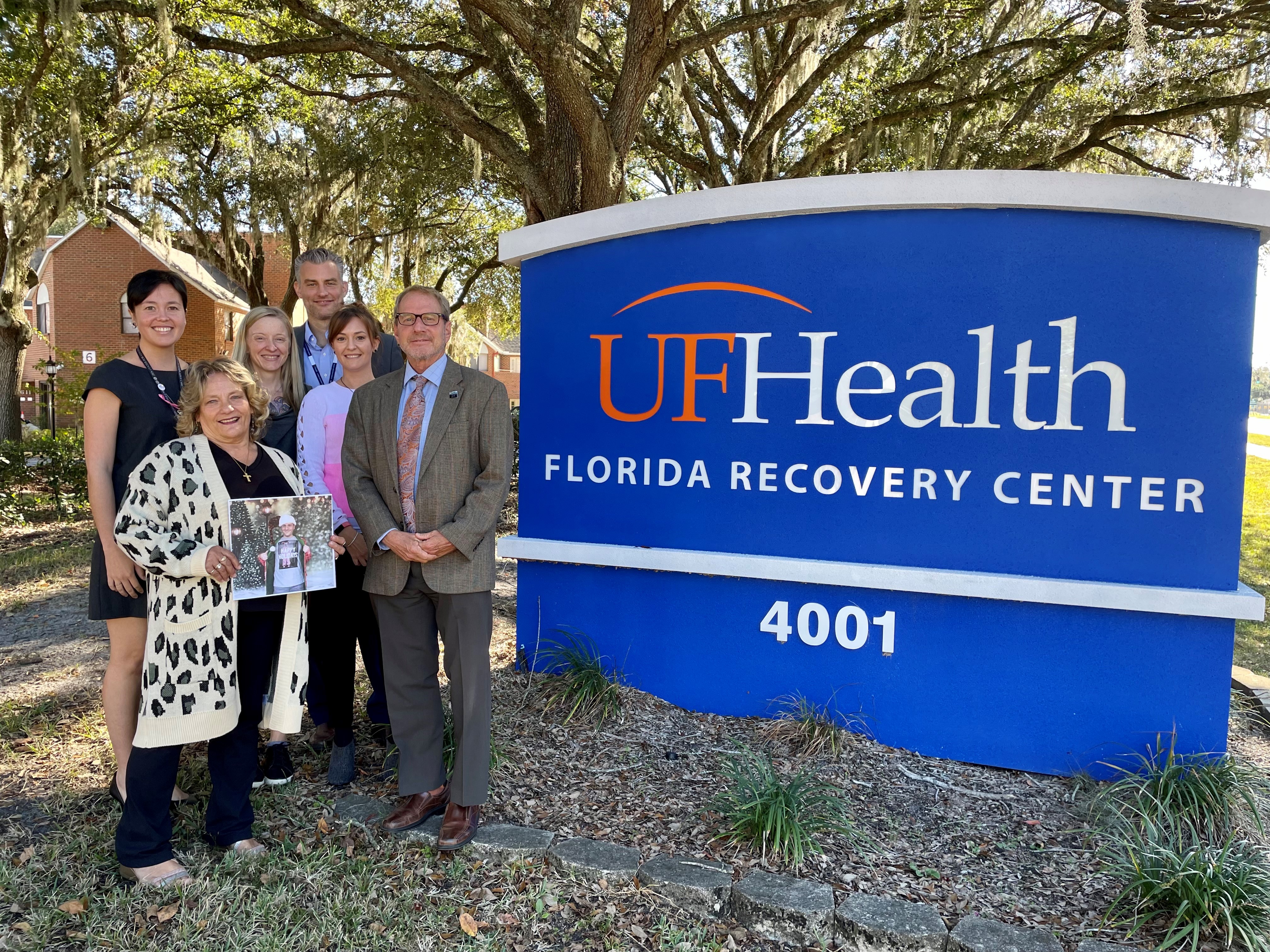Debbie Knight, front left, holds up a picture of her son, Ryan Brown, who passed away in July 2021. From back left: Vanessa Brown, Leslie Gray, LMHC, David Fields, LCSW, CAP, Rachel Waters, LMHC, Scott Teitelbaum, MD.