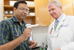 Dr. Mondal (l) and Hendeles demonstrate an Asthmanefrin atomizer, the device that turns the liquid racemic epinephrine into a mist that is inhaled by asthma patient. You can see the mist to the right of the mouthpiece.