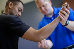 Jason Zaremski, M.D., CAQSM, assistant professor in the UF department of orthopedics and rehabilitation, examines a patient's elbow during an office visit.