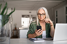 Woman at home on her computer and cell phone