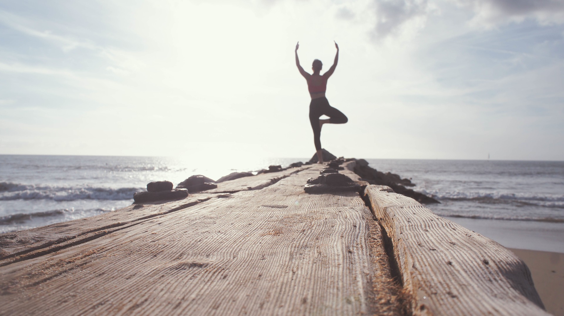 Woman doing yoga on a rocky pier. 