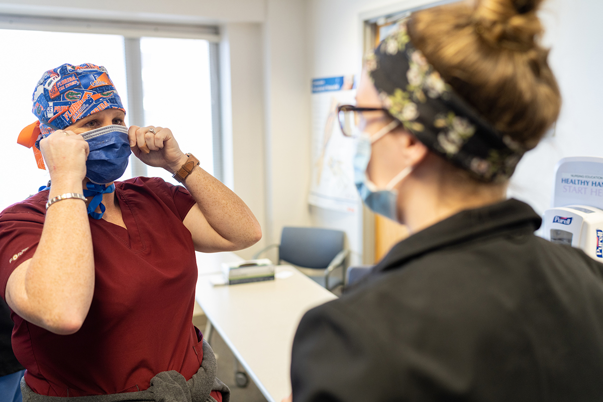 Two women health care providers talk while wearing masks. 