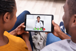two people look at a tablet with a doctor on the screen