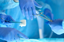hands in blue gloves holding surgical instruments