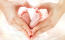 two hands making a heart around two baby feet