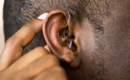 person touching a hearing aid in ear